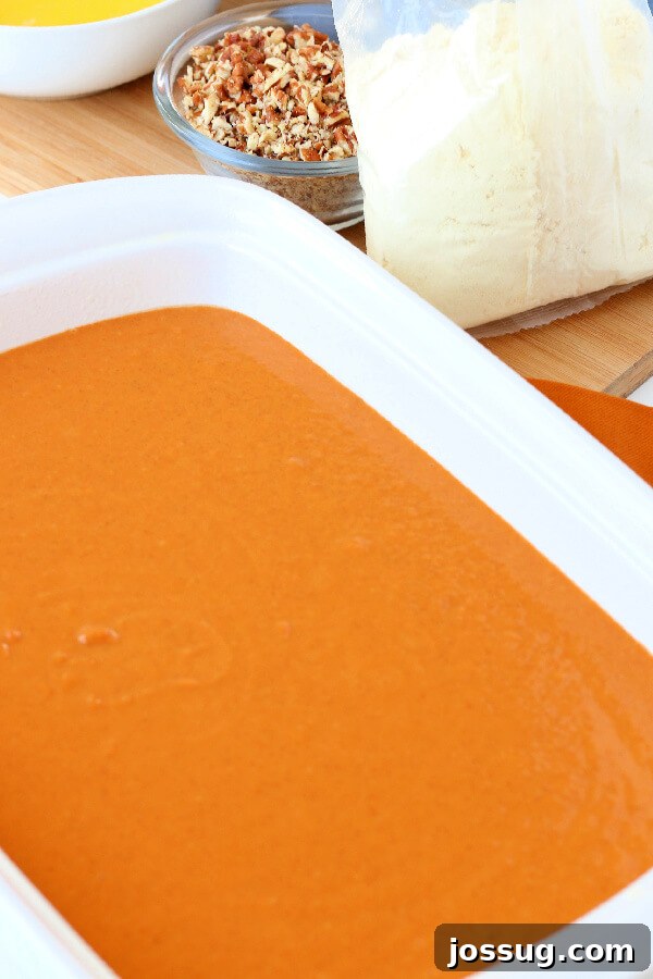 Spiced Pumpkin Crumble Bake 6 Close-up shot of the rich, orange pumpkin batter spread evenly in a 9x13-inch baking pan, ready for the topping layers.