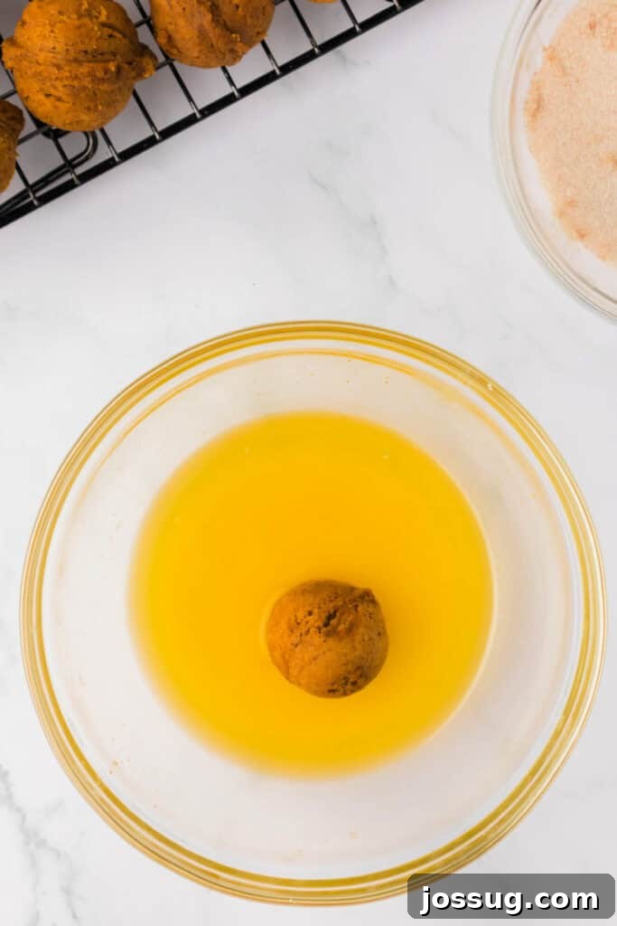 Pumpkin Poppers 11 Pumpkin donut hole dipped into melted butter, ready to be coated in cinnamon sugar.