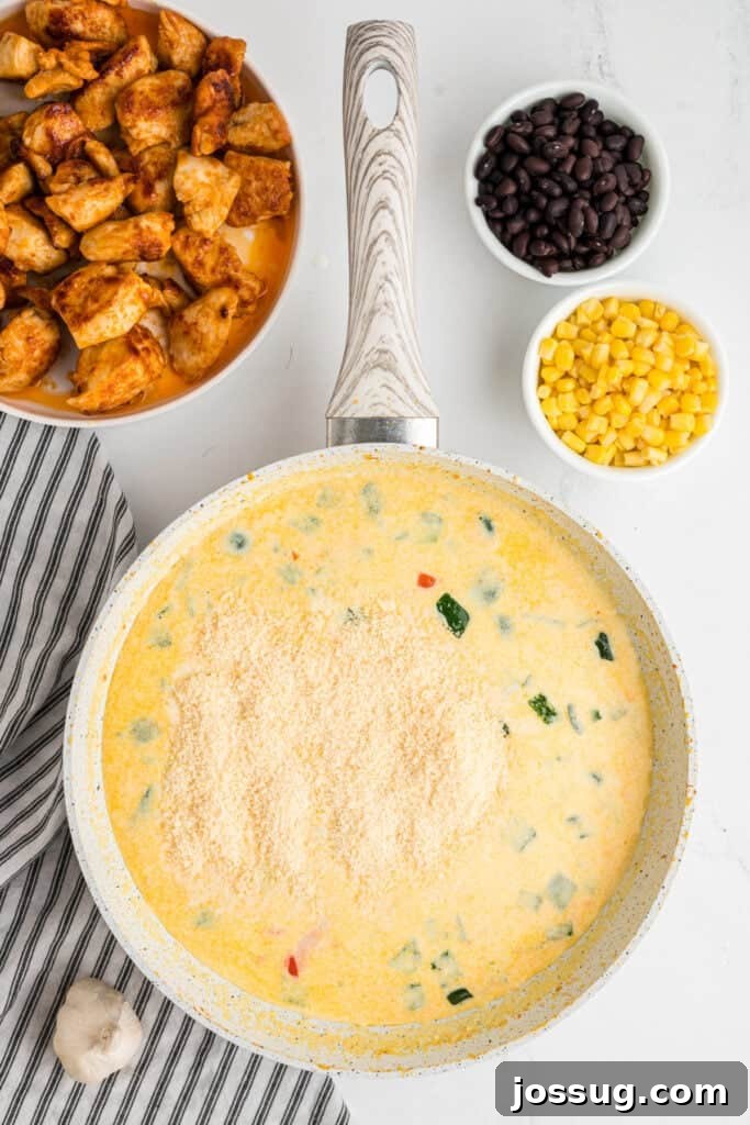 Fiesta Chicken Fettuccine Alfredo 11 Grated parmesan cheese being generously sprinkled into the creamy southwest alfredo sauce, stirring to melt.