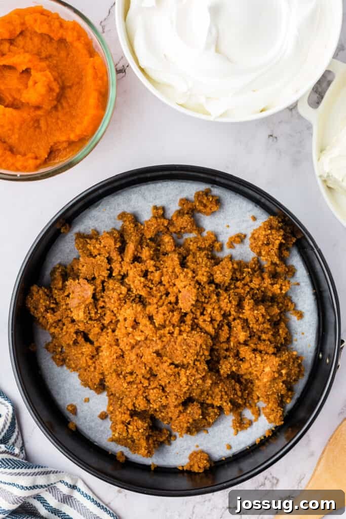 Decadent No-Bake RumChata Pumpkin Cheesecake 6 Graham cracker crust mixture added into the parchment-lined springform pan, ready to be pressed into place for the cheesecake base.