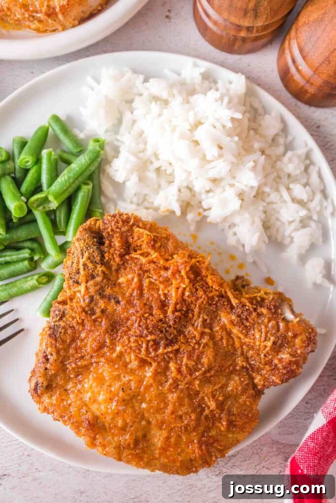 Golden Crispy Air Fried Bone In Pork Chops 2 Overhead view of crispy bone-in pork chop plated with green beans and rice, ready to serve.