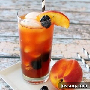 Orchard Peach Blackberry Teagarita 2 A Peach and Blackberry Teagarita in a glass with a peach next to the glass.