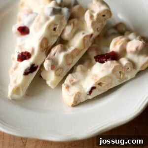 Ruby Cashew Crunch 2 A close-up shot of freshly made Cranberry Cashew Bark, showcasing its vibrant red cranberries and crunchy cashews embedded in white chocolate.