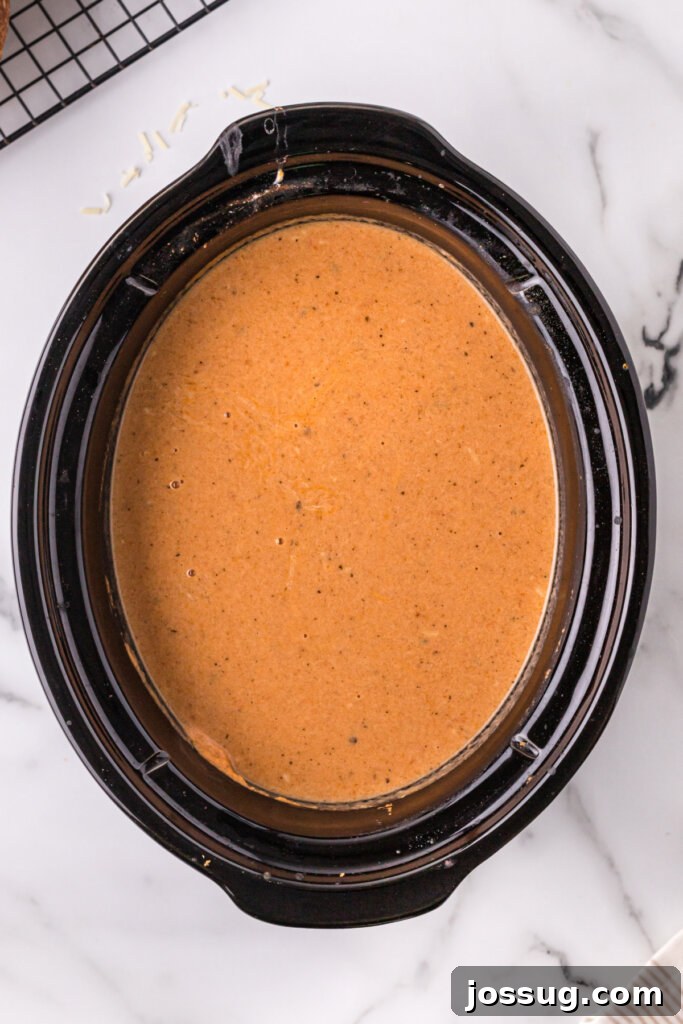 Creamy Slow Cooker Italian Parmesan Tomato Soup 3 Inside a slow cooker, a vibrant red tomato soup simmers, ready for its creamy additions.