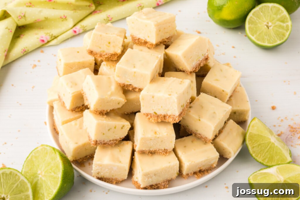 Several pieces of vibrant green key lime pie fudge, some stacked, some scattered, on a white plate ready to be enjoyed