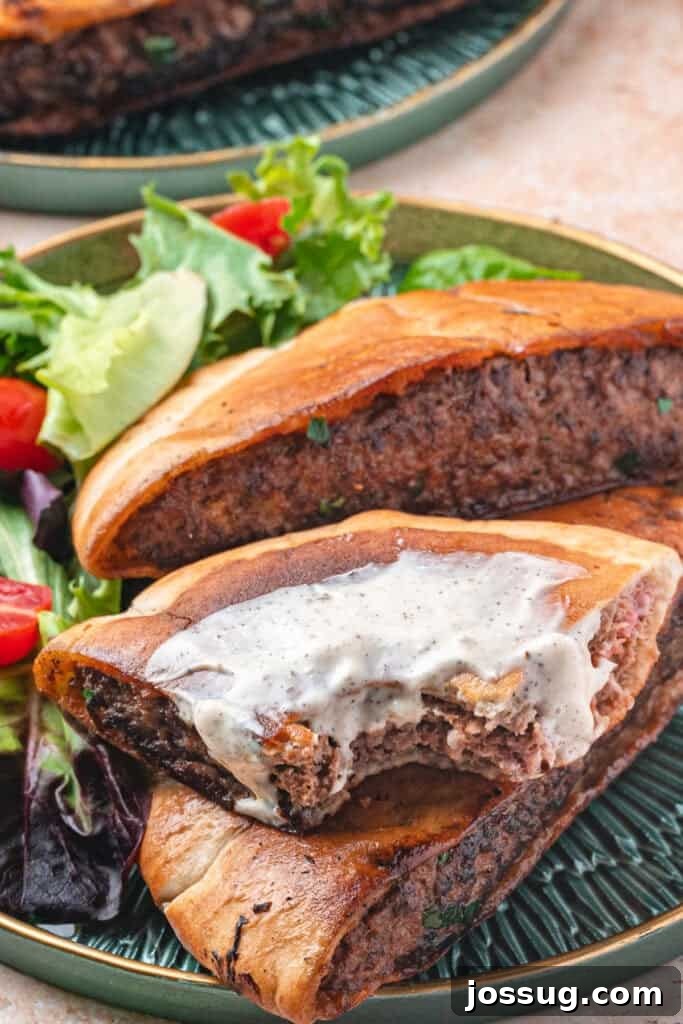 Arayes served on a green plate with salad, one piece topped with creamy shwarma white sauce and a bite taken to show texture.