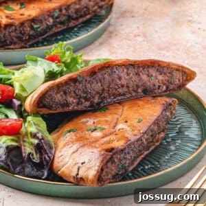 Square crop of arayes served on a green plate with salad, showing the crisp pita and spiced meat filling inside.