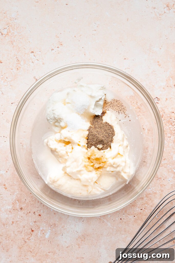 Bowl of mayonnaise, Greek yogurt, vinegar, minced garlic, sugar, salt, and black pepper before whisking into shwarma white sauce.