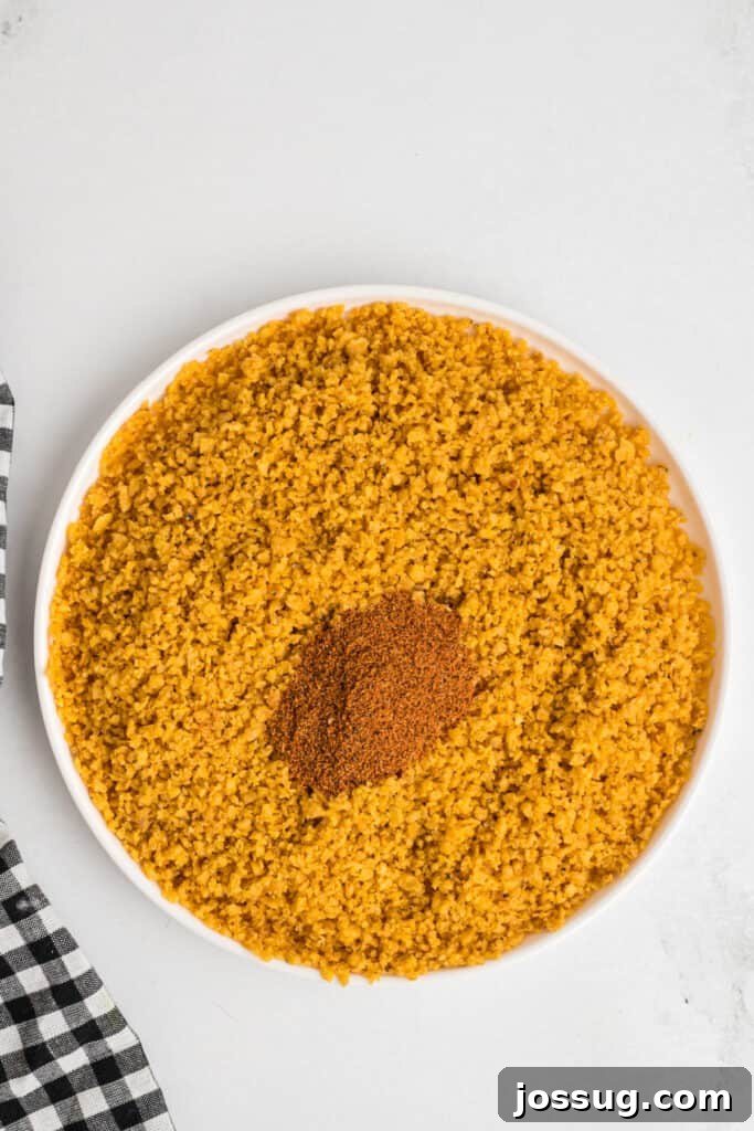 Bowl of crushed corn chips mixed with ancho chili powder for coating southwest chicken tenders, ready for breading.