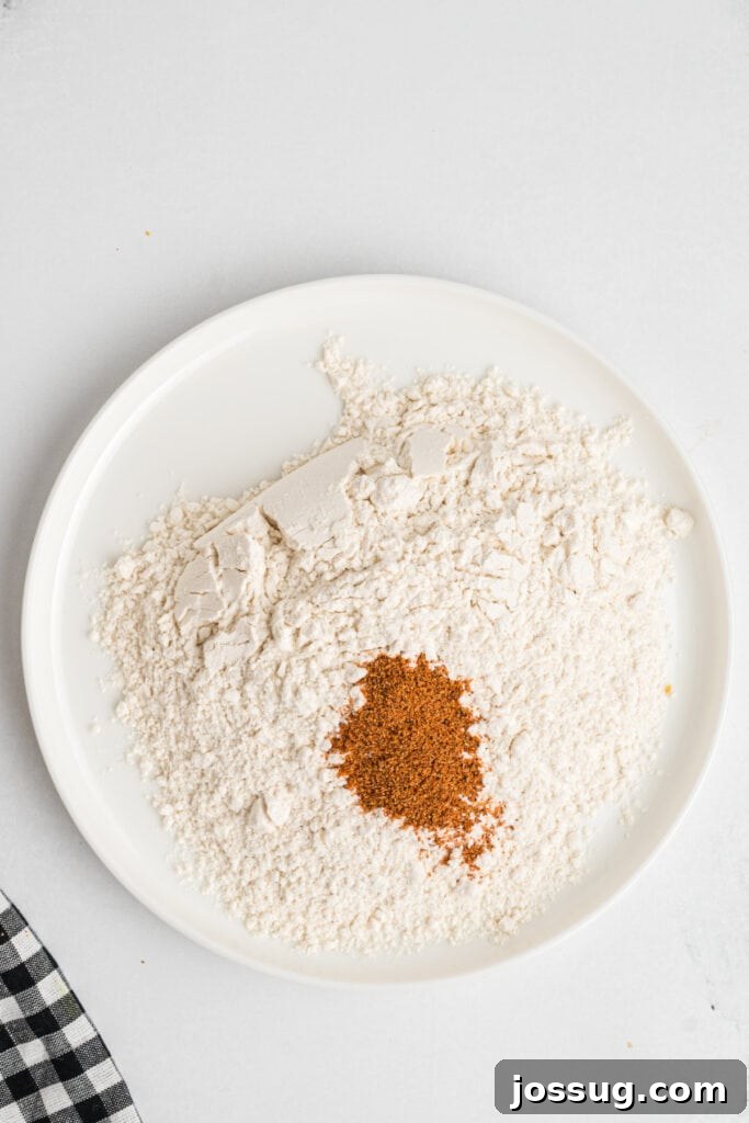 Plate of all-purpose flour with ancho chili powder mixed in for dredging chicken tenders, forming the initial layer.