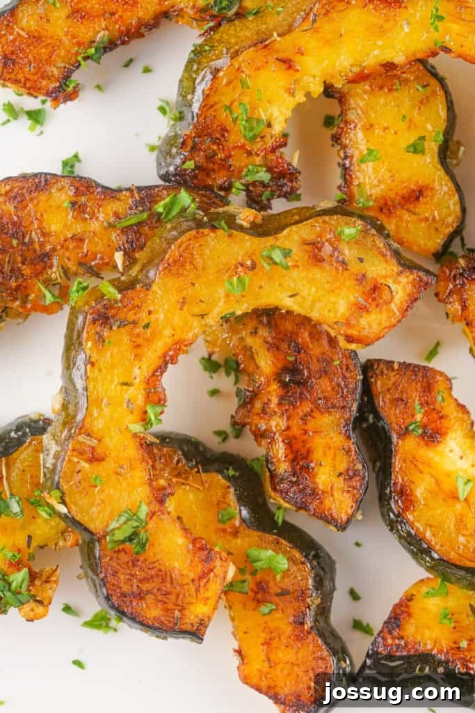 Caramelized Acorn Squash 2 Overhead view of golden roasted acorn squash slices garnished with parsley on a white plate.