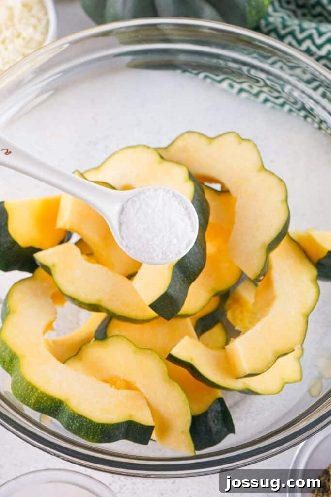 Caramelized Acorn Squash 4 Spoonful of coarse salt being added to sliced raw acorn squash in a mixing bowl.