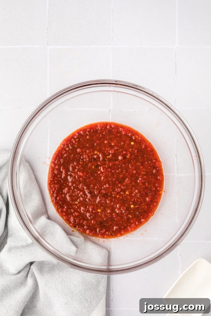 Smoky Sweet Air Fryer Chipotle Honey Glazed Wings 11 Chipotle honey sauce transferred into a glass bowl, smooth and vibrant red with specks of seasoning.