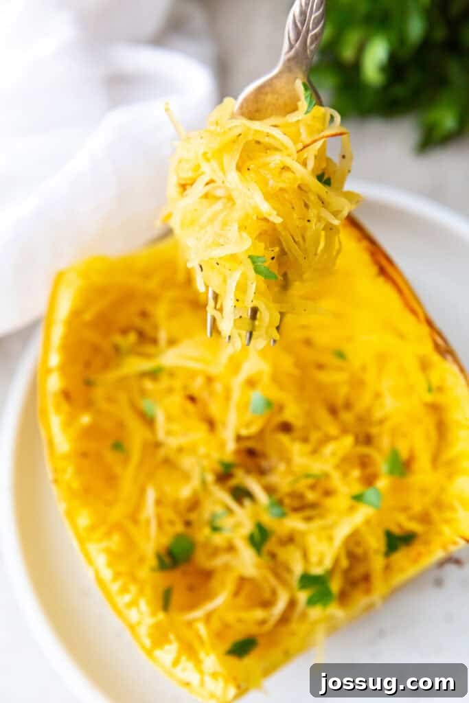 Cooked spaghetti squash strands lifted with a fork, garnished with parsley, inside the squash shell.