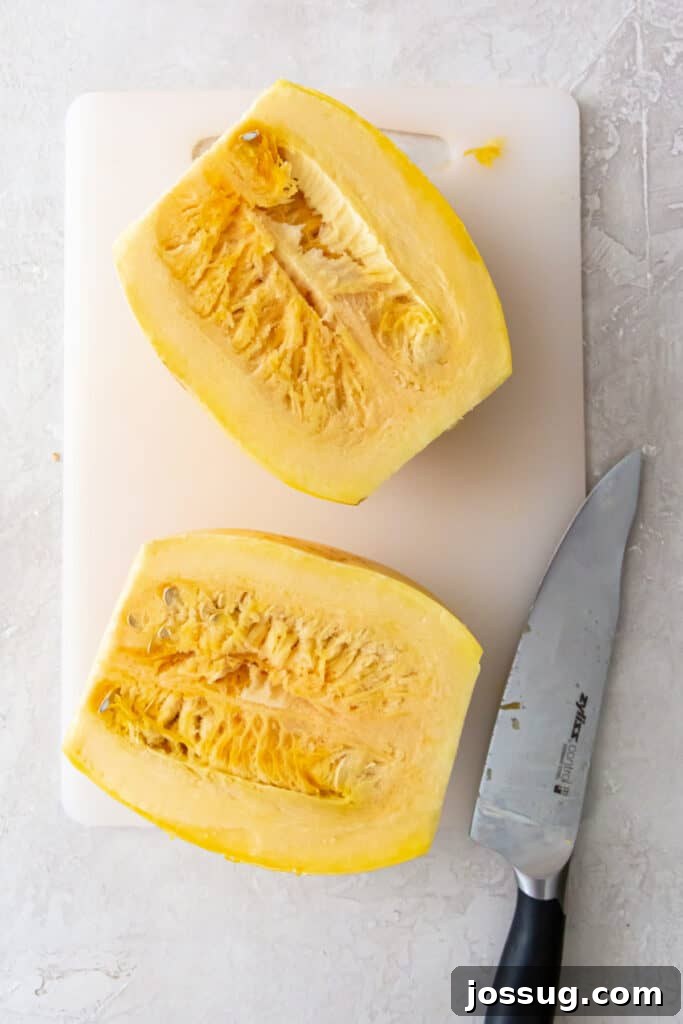 Spaghetti squash sliced in half lengthwise on a cutting board, showing the inside with seeds.