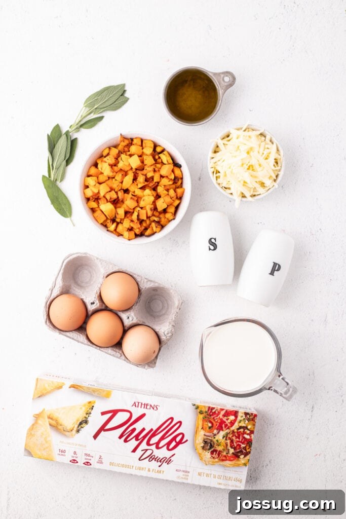 Overhead view of ingredients for roasted squash quiche including roasted butternut squash, fresh sage, olive oil, eggs, phyllo dough, shredded Gruyère cheese, half and half, and salt and pepper shakers.