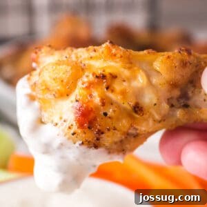 Crispy air fryer lemon pepper chicken wing being dipped into creamy ranch dressing.