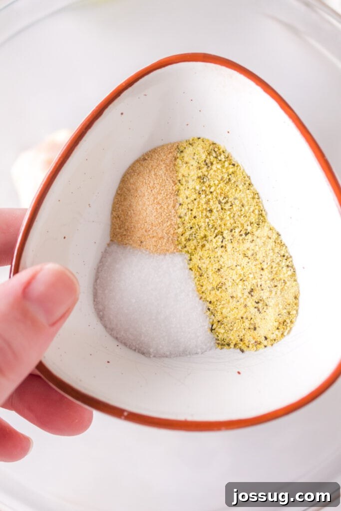 Close-up of a small bowl holding lemon pepper, garlic powder, and salt seasoning.