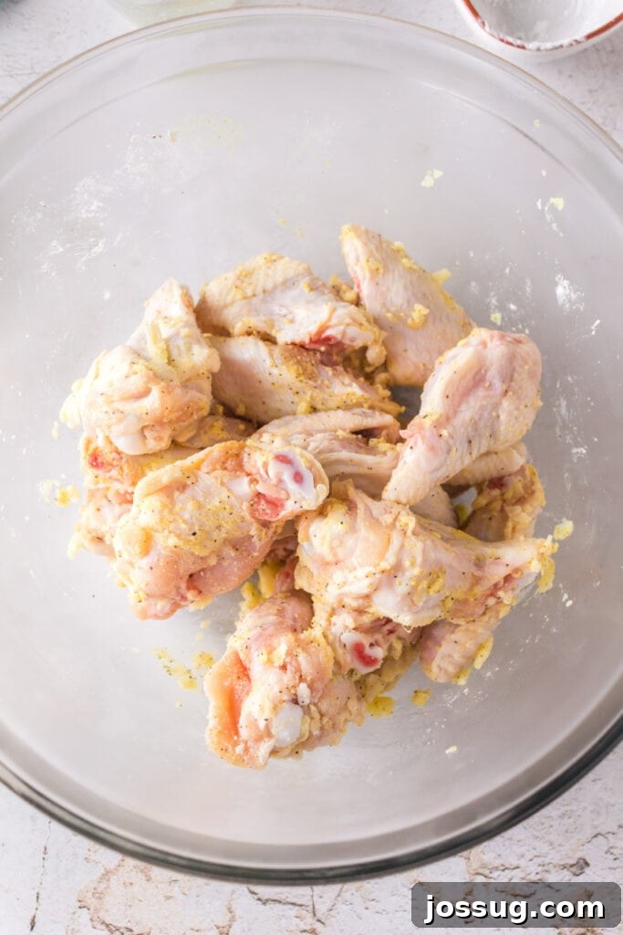 Crispy Air Fryer Lemon Pepper Wings 9 Seasoned and coated raw chicken wings tossed together in a mixing bowl.