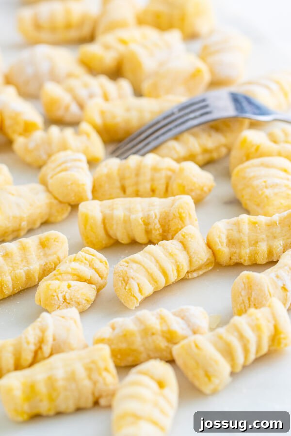 Pillowy Soft Potato Gnocchi 2 Freshly rolled homemade potato gnocchi dough, cut into pieces and ready for shaping on a white floured surface