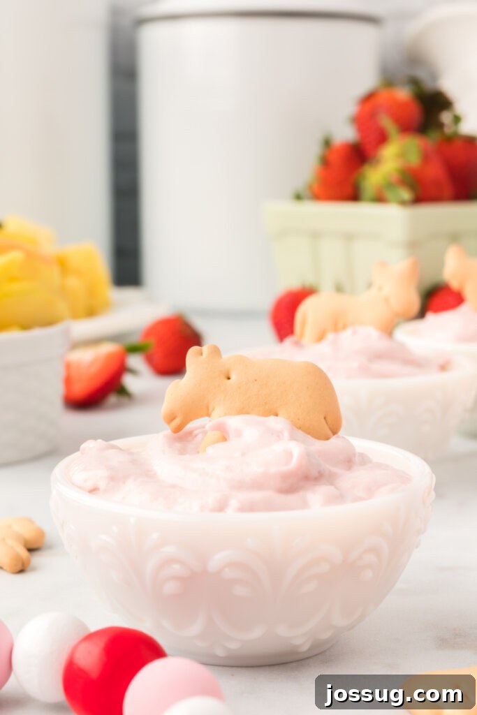 animal cracker in strawberry cream cheese dip
