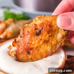 Close-up square photo of crispy air fryer ranch wings dipped in creamy ranch sauce