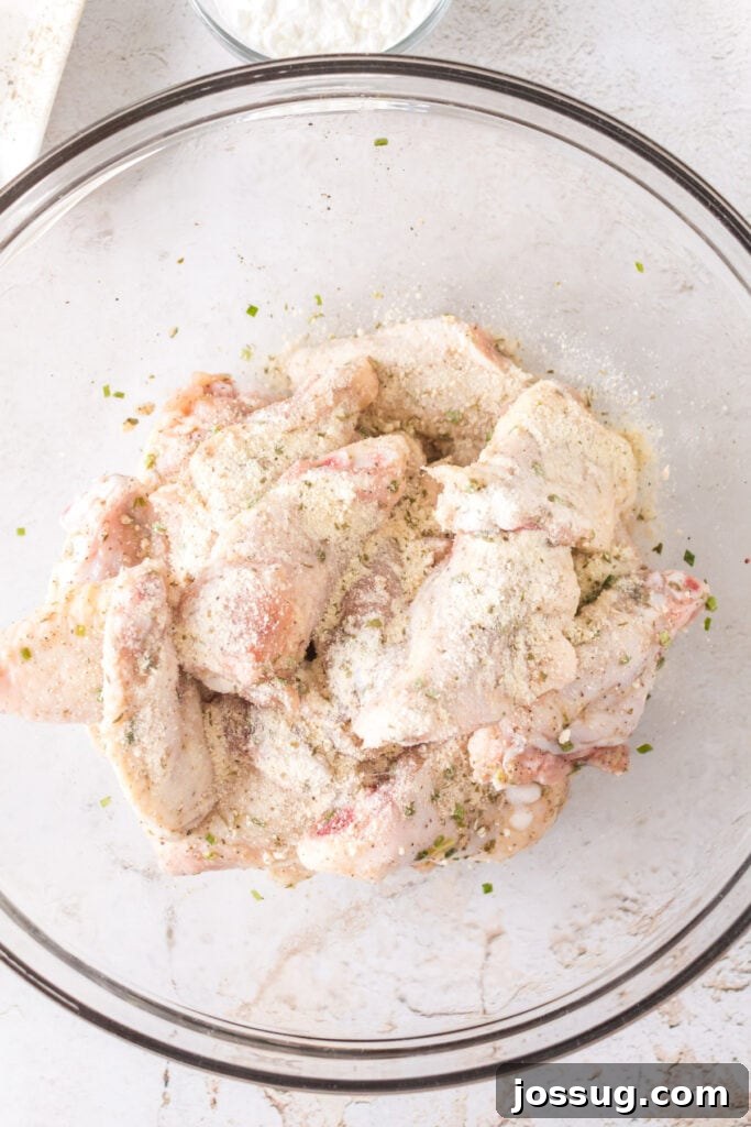 Crispy Air Fryer Ranch Wings 7 Raw chicken wings coated with ranch seasoning mix and herbs in a glass bowl