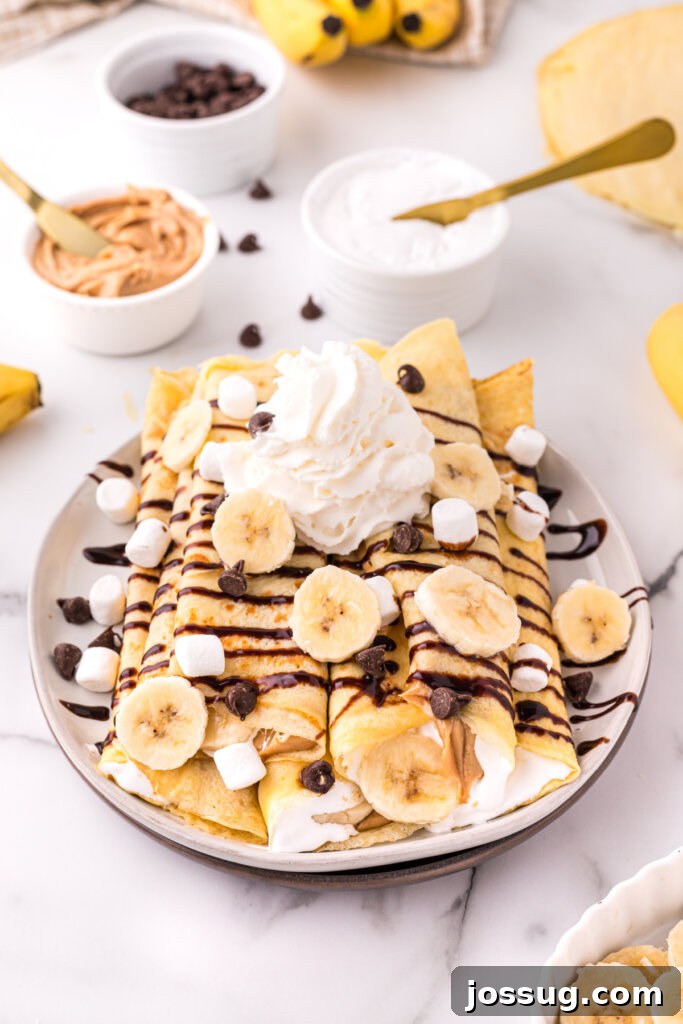 Decadent Banana Fluffernutter Crepes 3 Appetizing banana fluffernutter crepes, garnished with banana slices, a generous drizzle of chocolate syrup, and a swirl of whipped topping.