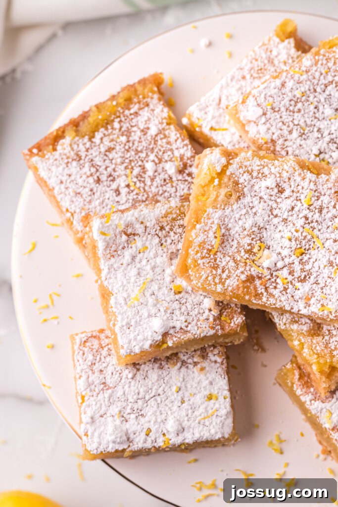 A stack of perfectly cut lemon bars, dusted with powdered sugar, ready to be served.