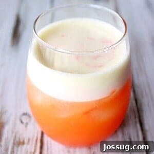 Oasis Refresh 2 A glass of vibrant Cactus Cooler, garnished with citrus wedges, on a warm weather backdrop.