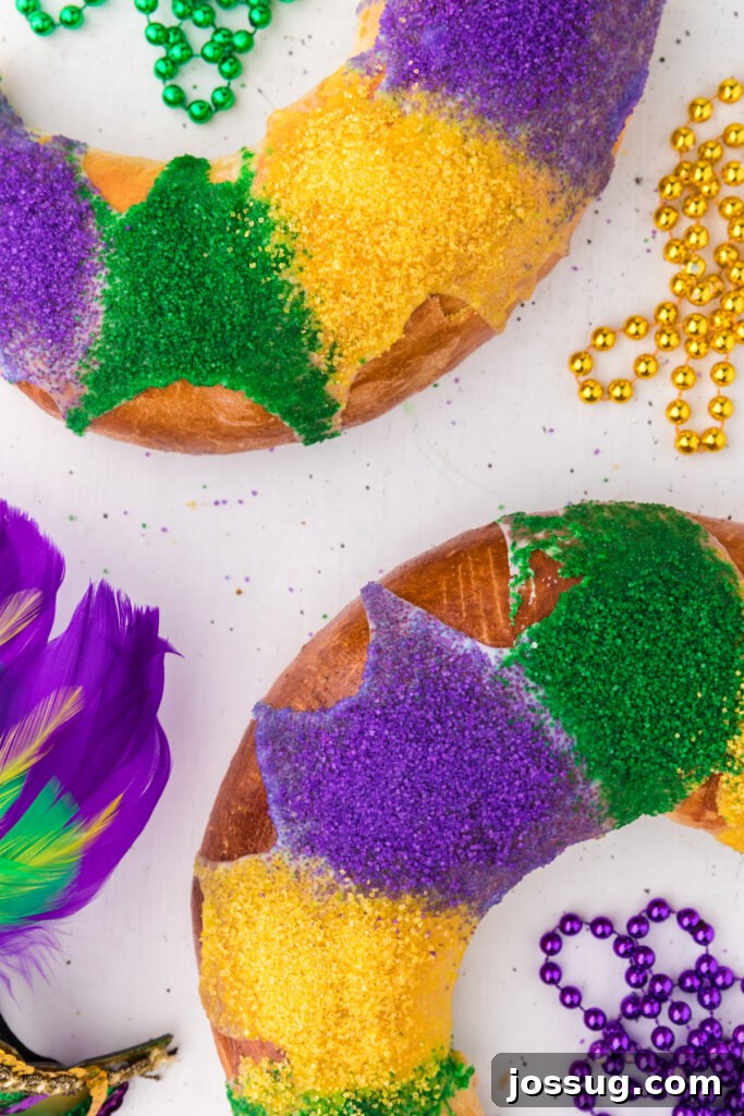 New Orleans Mardi Gras King Cake 5 A beautifully decorated New Orleans King Cake covered in white glaze and generous sprinkles of purple, green, and yellow sugar, ready for celebration.