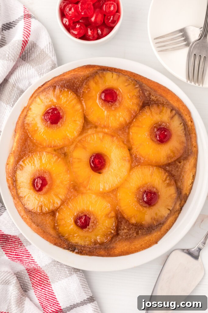 Golden pineapple upside-down cake served on a white plate, showcasing the caramelized pineapple slices and maraschino cherries