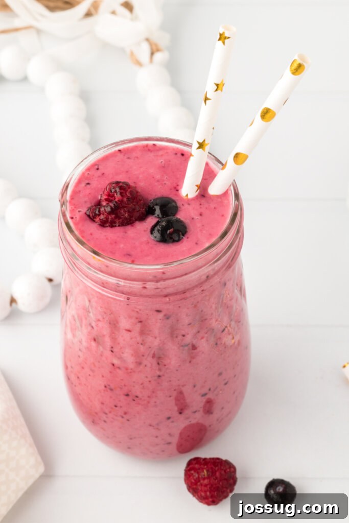 banana berry smoothie in a glass, garnished with fresh berries