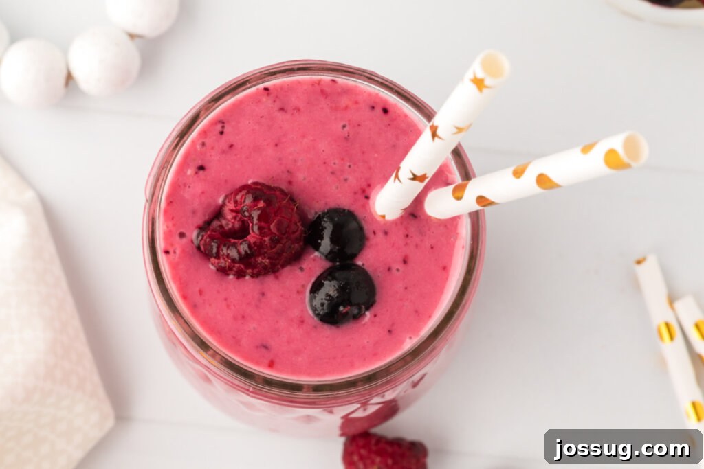 looking down into a glass with banana berry smoothie, with a spoon