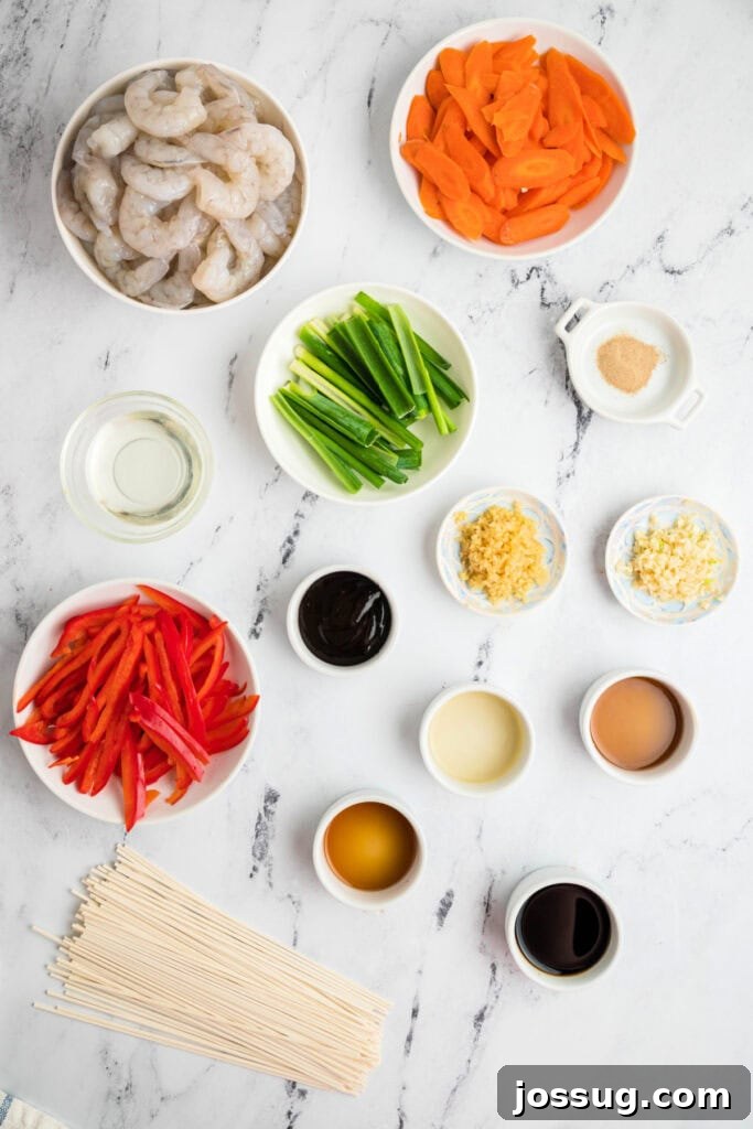 Overhead view of raw shrimp, sliced carrots, red bell pepper, green onions, minced garlic, fresh ginger, and lo mein sauce ingredients laid out neatly on a marble surface, ready for cooking.