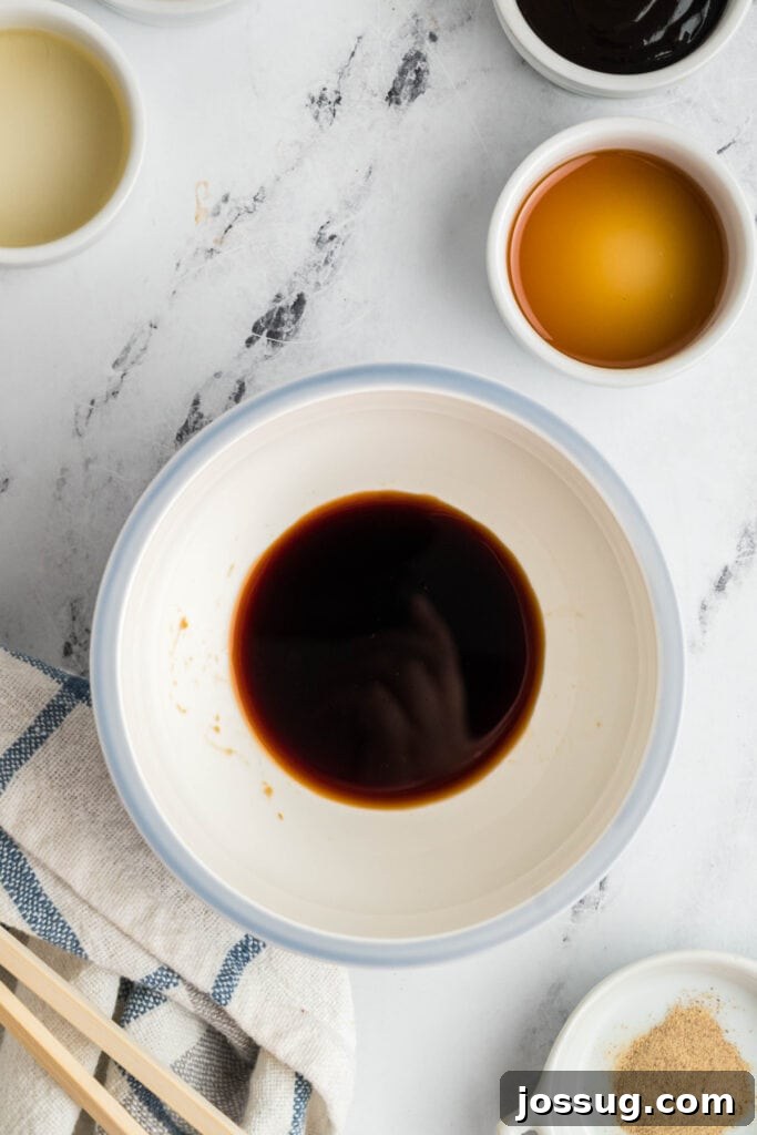 Small bowl of soy sauce mixture starting the lo mein sauce with other ingredients nearby, showcasing the sauce preparation.