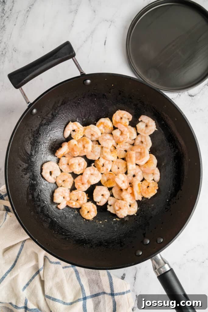 Shrimp cooking in a wok until pink and lightly browned, showing the progress of the stir-fry.