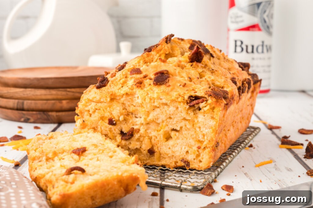 Smoked Bacon & Cheddar Ale Loaf 6 a whole loaf of bacon cheddar beer bread with one slice cut, ready to be served