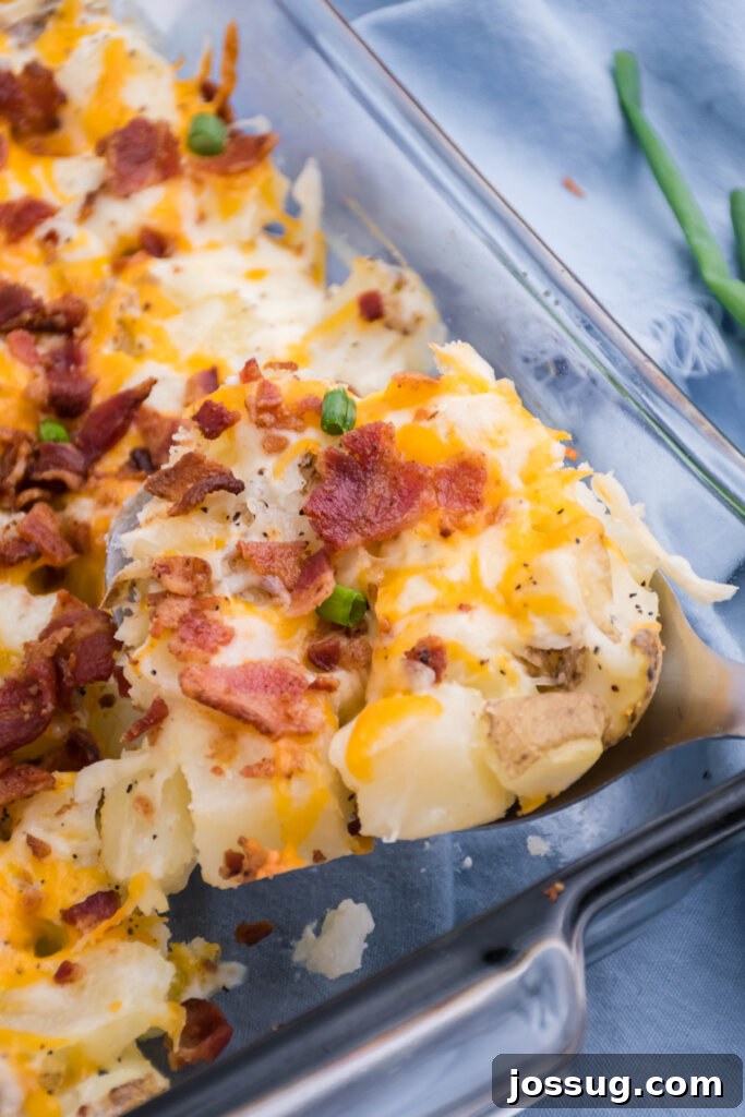 A close-up shot of a creamy, golden-brown Twice-Baked Potato Casserole in a glass baking dish, showing the melted cheese and bacon topping. Perfect for any meal.