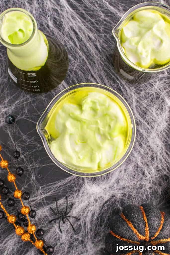 Biohazard Brew 15 Multiple beakers of Toxic Waste Punch, each generously topped with fluffy green foamy whipped cream swirled artfully on top, creating a captivating spooky bubbling effect.