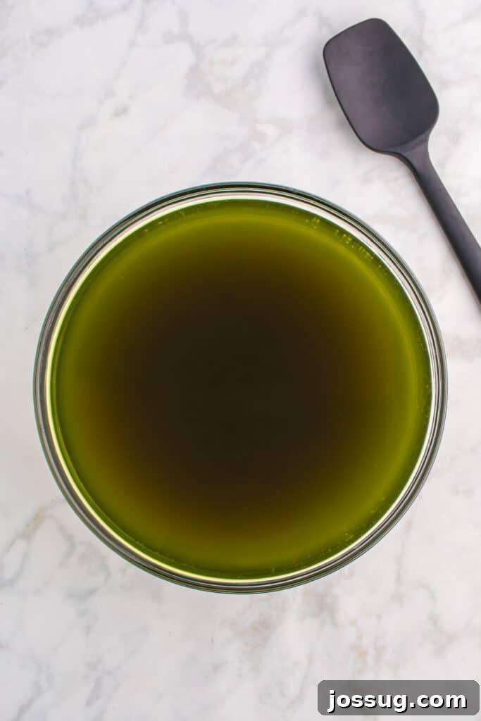 Biohazard Brew 7 Large glass bowl of dark green punch after food coloring is added, with a black spatula and green food coloring bottle resting on the side, demonstrating the color transformation.