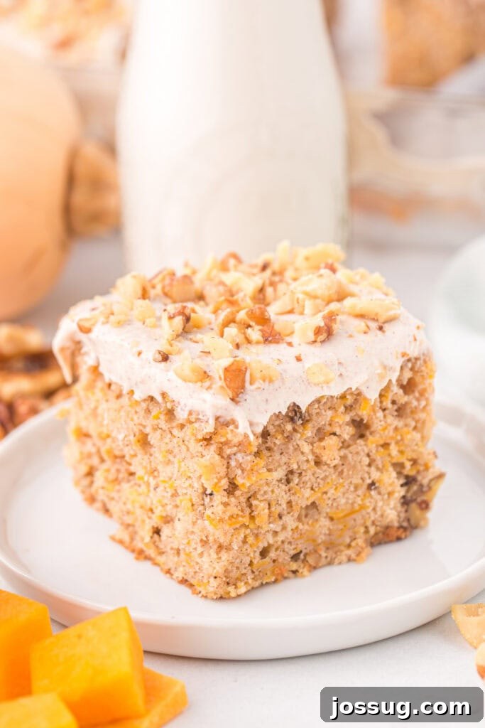 Spiced Golden Butternut Cake 2 A delectable slice of butternut squash cake rests on a pristine white plate, adorned with a swirl of creamy frosting and a sprinkle of chopped walnuts. A rustic milk bottle softly blurs in the background, hinting at cozy fall moments.