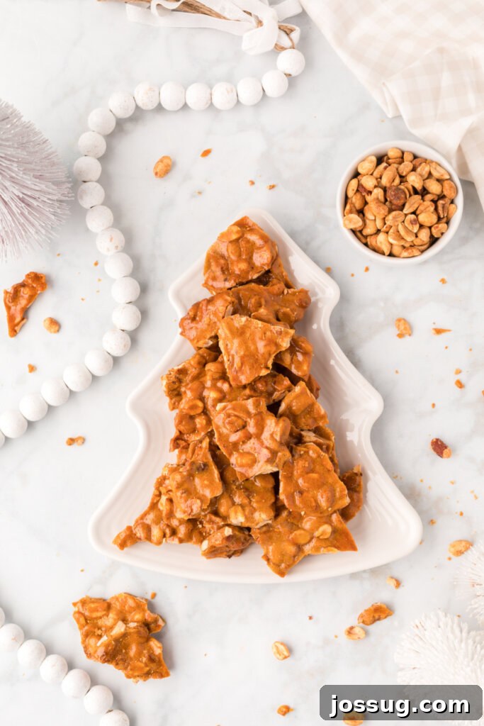 Peanut brittle pieces elegantly arranged on a holiday-themed plate with festive decorations.