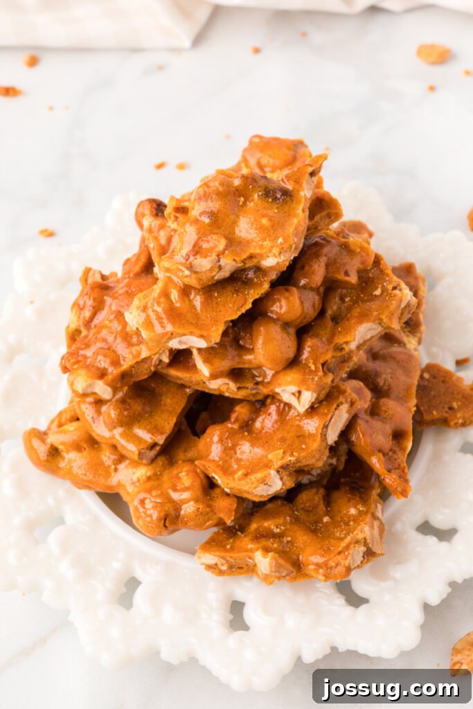 A top-down view of microwave peanut brittle artfully arranged on a simple white plate.
