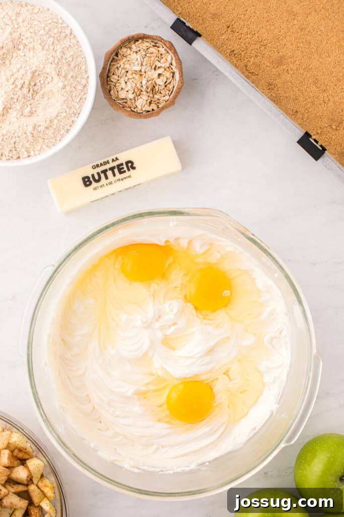 Cream cheese filling in a bowl with cracked eggs added before being gently incorporated into the batter.