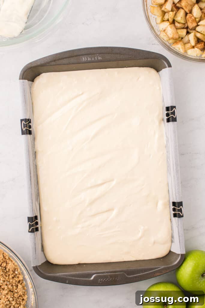 Evenly spread cheesecake layer over the graham cracker crust in a 9x13-inch pan, forming the second layer.
