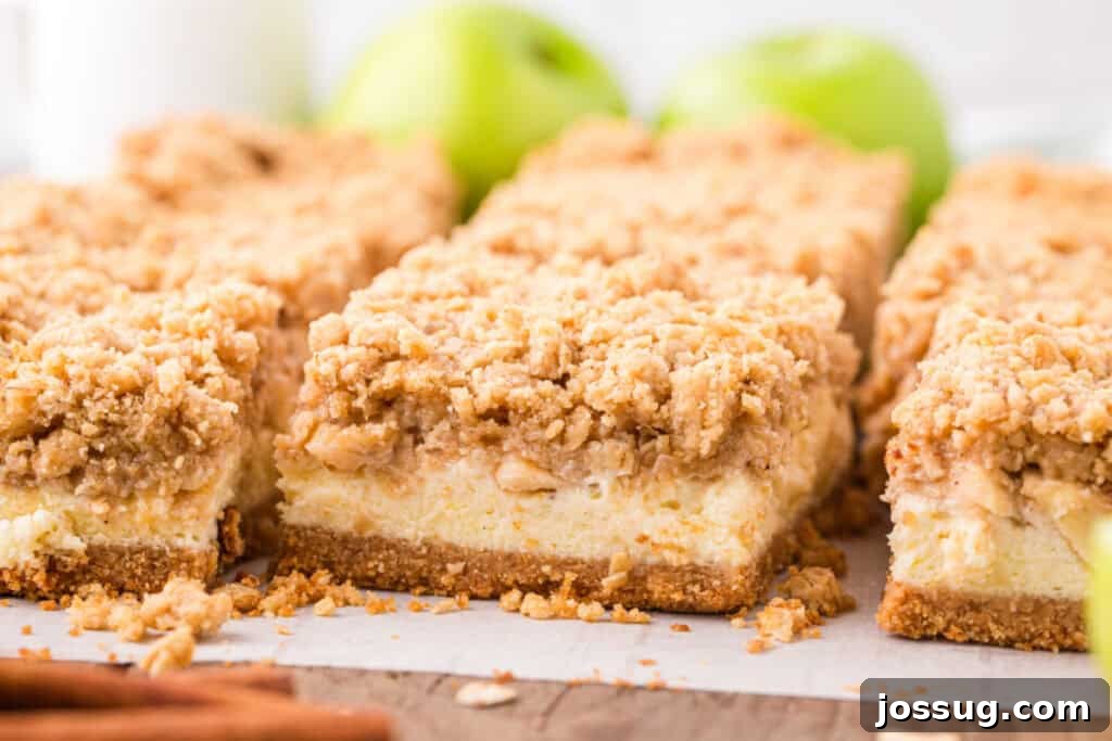 Close-up of perfectly sliced caramel apple cheesecake bars showing creamy cheesecake and crumb topping, ready to serve.
