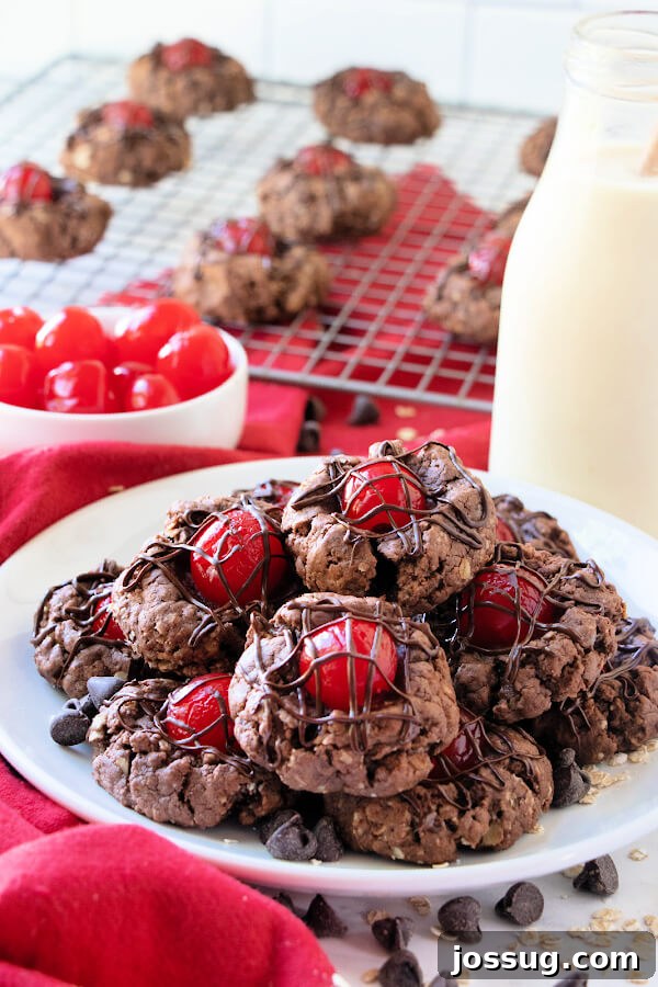 Decadent Chocolate Cherry Thumbprints 7 Chocolate Cherry Thumbprints Cookies on a plate with a glass milk bottle and a bowl of fresh cherries