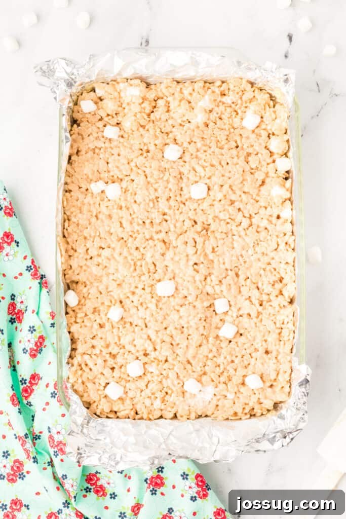 Caramelized Butter Rice Crisps 12 Browned Butter Rice Crispy Treats pressed into a foil-lined pan, cooling before cutting into squares.