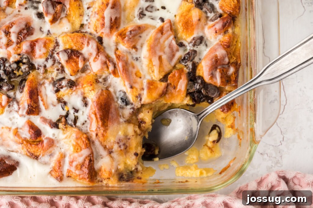 Warm Cinnamon Roll Bread Bliss 5 Cinnamon Roll Bread Pudding in a pan with a serving spoon